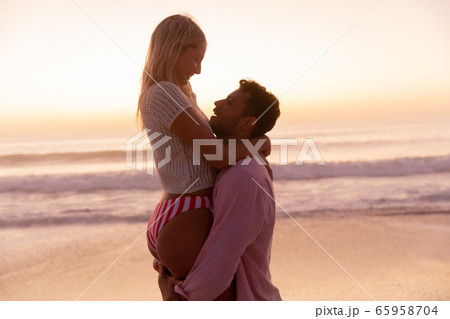 Caucasian couple enjoying time at the beach during the sunset Caucasian couple enjoying time at the beach during the sunset 65958704