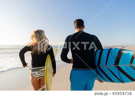 Caucasian couple holding surfboards at the beach. 65958718