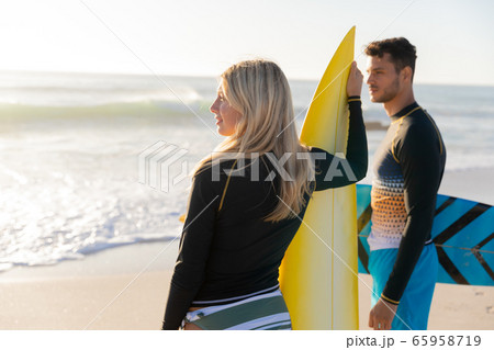 Caucasian couple holding surfboards at the beach. 65958719