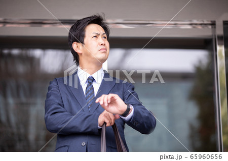 腕時計を見ながら待ち合わせするアジア人ビジネスマン 65960656