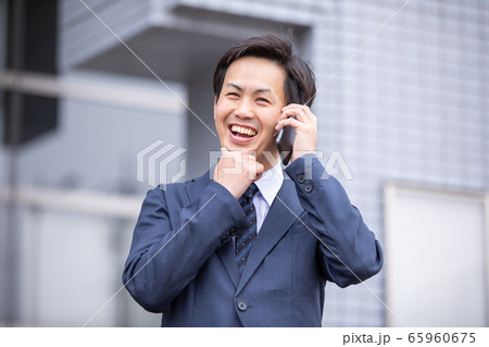 楽しくスマホで電話するアジア人ビジネスマン（笑顔） 65960675