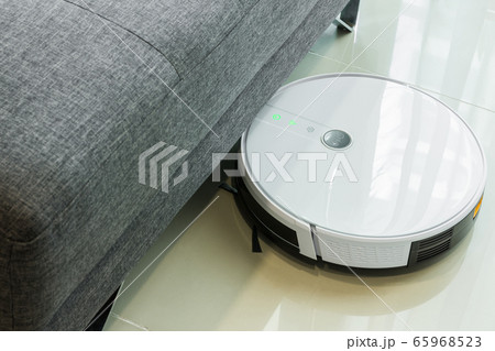 Robotic vacuum cleaner cleaning the floor under the sofa. Robotic vacuum cleaner cleaning the floor under the sofa. 65968523