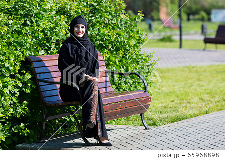 A beautiful young muslim woman is sitting on a A beautiful young muslim woman is sitting on a 65968898