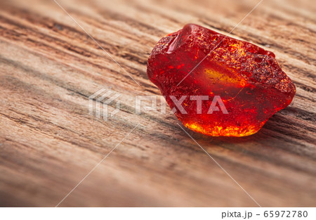 Natural amber. A piece of yellow transparent natural amber on a piece of textured wood Natural amber. A piece of yellow transparent natural amber on a piece of textured wood 65972780