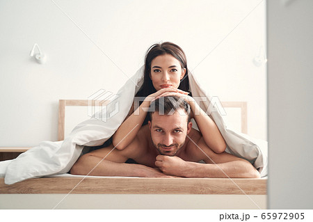 Young couple relaxing under the duvet in a bedroom 65972905