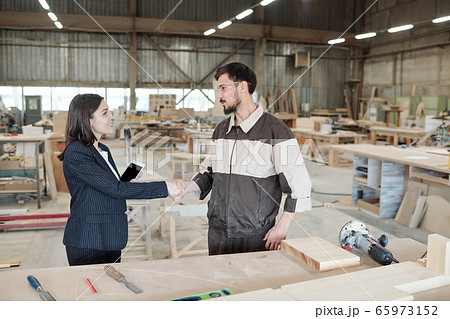 Pretty young female manager or business partner shaking hand of worker 65973152
