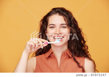 Young laughing brunette woman with healthy smile brushing her teeth 65973247