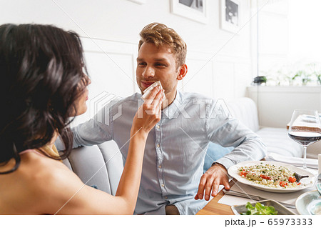 Young lady wiping gentleman mouth with napkin in cafe 65973333