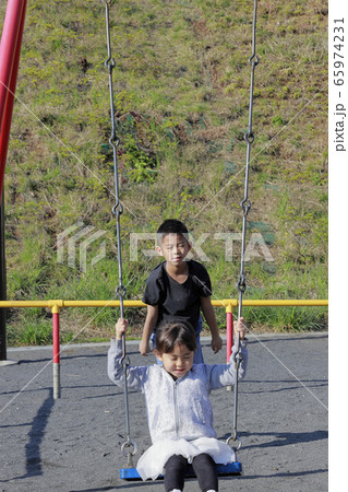 ブランコで遊ぶ妹と背中を押す兄(10歳と5歳) 65974231