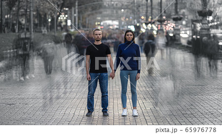 The man and woman stand on the crowded street and hold hands The man and woman stand on the crowded street and hold hands 65976778