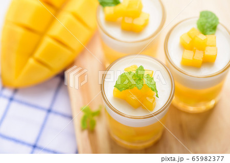Thai dessert mango pudding, ripe mango dip in agar and coconut milk jelly on top in the glass Thai dessert mango pudding, ripe mango dip in agar and coconut milk jelly on top in the glass 65982377