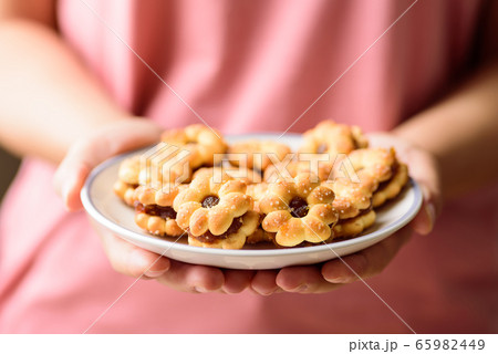Cracker with pineapple jam (flower shape) on plate holding by woman hand, Thai snack Cracker with pineapple jam (flower shape) on plate holding by woman hand, Thai snack 65982449
