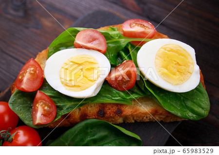 Tasty bruschettas with spinach and eggs. Tasty bruschettas with spinach and eggs. 65983529
