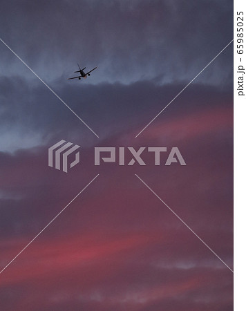 夕焼け空に向かって輝きながら飛び立つ飛行機の後ろ姿 65985025