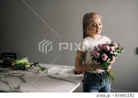 Beautiful young woman wearing fashion clothes holding bouquet of flowers 65985282