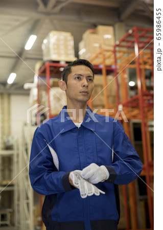 Young man in work gloves in warehouse with cargo trolley Stock