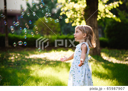 Portrait of funny lovely little girl blowing soap bubbles Portrait of funny lovely little girl blowing soap bubbles 65987907