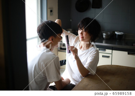 男性の髪を切る女性 65989158