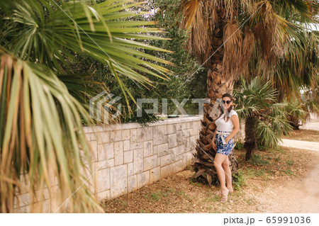 Young woman in blue shorts walking outdoors alone alond the street. Tropical 65991036