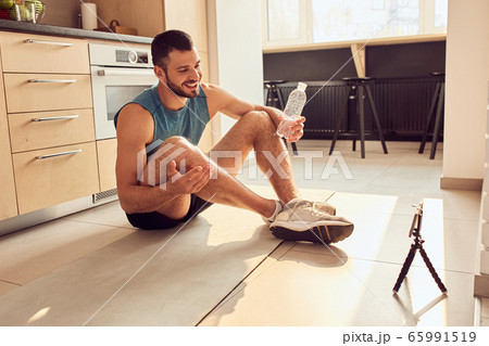 Cheerful young man chatting with gym instructor online Cheerful young man chatting with gym instructor online 65991519