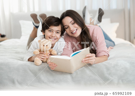 Woman reading a book for her son 65992109