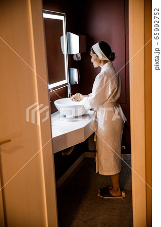 Cheerful pretty woman washing hands in bathroom Cheerful pretty woman washing hands in bathroom 65992752