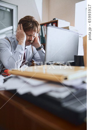 Mature businessman going through stress situation at his working desk Mature businessman going through stress situation at his working desk 65993917