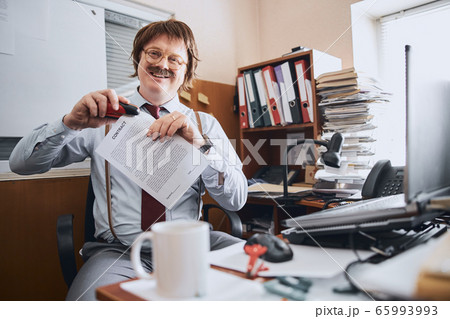 Glad office worker stapling pages of an important paper document 65993993