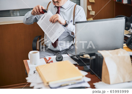 Old-fashioned man joining parts of a contract together with stapler 65993999