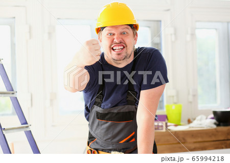 Smiling funny worker in yellow helmet posing 65994218