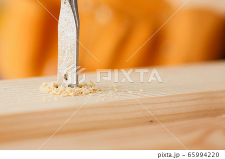 Flat drill bit make hole in wooden bar closeup 65994220