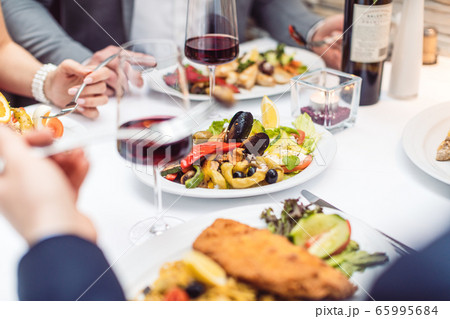 Close-up on Italian food on the table in restaurant with people eating 65995684