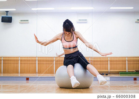 バランスボールに挑戦する若い女性 バランスボールに挑戦する若い女性 66000308
