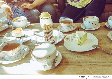 Happiness female friends meeting and drinking tea or coffee with cakes together at cafe in the afternoon. People, leisure and communication concept. Selective focus. 66002082
