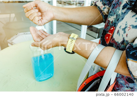 Woman uses her hand to press hand sanitizer bottle to clean her hand at wayside in the city. Concepts of Flu virus, Covid-19 (Coronavirus disease). Selective focus on alcohol gel bottle. Woman uses her hand to press hand sanitizer bottle to clean her hand at wayside in the city. Concepts of Flu virus, Covid-19 (Coronavirus disease). Selective focus on alcohol gel bottle. 66002140