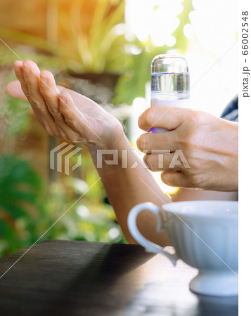 Woman using alcohol nano mist sprayer antiseptic cleaning on her hands protection during Coronavirus pandemic Covid-19.Hand using sanitizer spray.Modern health technology concept.New normal lifestyle. 66002548