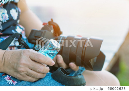 Hand of woman using alcohol nano mist sprayer antiseptic cleaning on camera protection during Coronavirus pandemic Covid-19. Wipe clean the surfaces with disinfectant. Modern health technology. 66002623