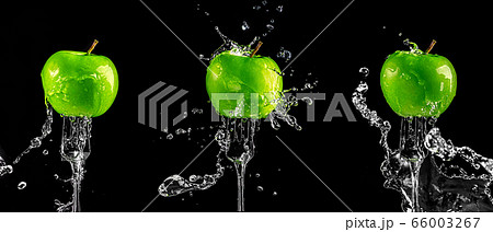 three green apples on a fork in splashes of water on a black background three green apples on a fork in splashes of water on a black background 66003267