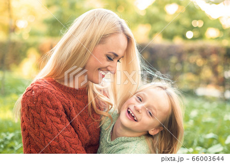 Portrait of young mother playing with her daughter in autumn park. 66003644