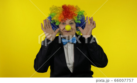 Senior old woman clown in colorful wig smiling, making silly faces, fool around 66007757