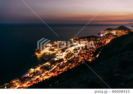 Aerial top night view on the old city of Dubrovnik, from the observation deck on the mountain above the city. Film location. The view of the city is based on the Royal Harbor. Aerial top night view on the old city of Dubrovnik, from the observation deck on the mountain above the city. Film location. The view of the city is based on the Royal Harbor. 66008433