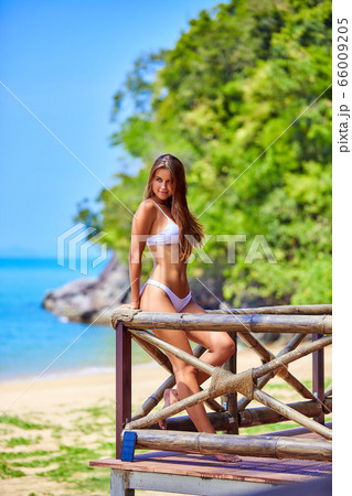 Beautiful girl in white bikini posing in bungalow 66009205