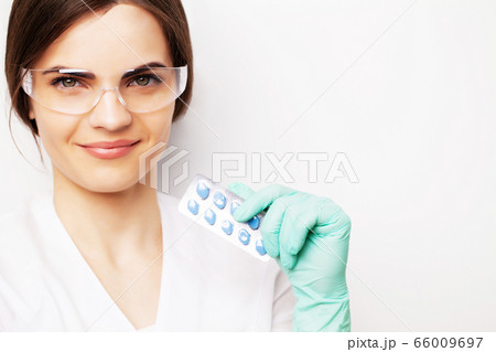 Sexual health, a doctor in a white coat holding a pill for a healthy sex life of men Sexual health, a doctor in a white coat holding a pill for a healthy sex life of men 66009697