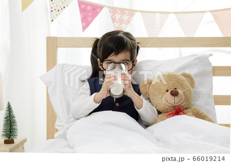 Little asian girl drinking some milk on the wooden bed in her bedroom, Preschooler girl drinking some milk with glass on sunny day, Educational concept for school kids. Little asian girl drinking some milk on the wooden bed in her bedroom, Preschooler girl drinking some milk with glass on sunny day, Educational concept for school kids. 66019214