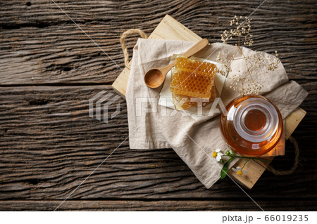 Honey bee in jar and honeycomb with honey dipper and flower on wooden table, bee products by organic natural ingredients concept, copy space for your text 66019235