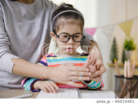 Mom teaching her daughter to writing in the book on the table, Educational concept for school 66019461