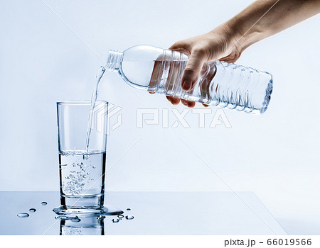Hand pouring fresh pure water from bottle into a glass on the table with water drops, Healthcare and beauty hydration concept Hand pouring fresh pure water from bottle into a glass on the table with water drops, Healthcare and beauty hydration concept 66019566
