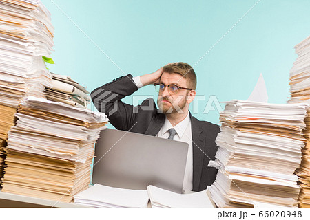 Shocked businessman sitting at the table with many Shocked businessman sitting at the table with many 66020948