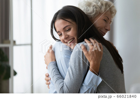 Grownup adult granddaughter embraces elderly grandmother glad to see her 66021840