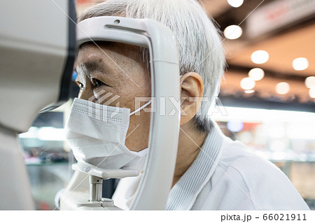 Asian senior woman having eyesight test using tonometer looking into the machine,old elderly patient checks her vision,eye examination by ophthalmlogist,presbyopia problems,health care at eye clinic 66021911